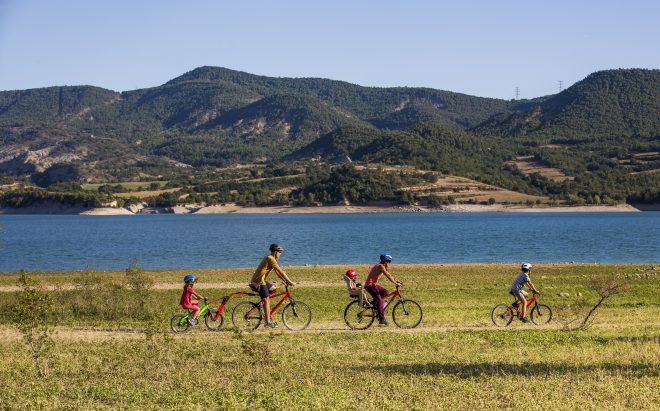 Una família ciclista per un camí de Terres de Lleida, amb la muntanya al fons